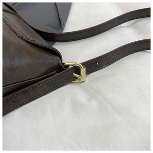 Close-up of dark brown leather tote bag showing adjustable strap and gold metal buckle