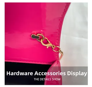 Close-up of golden hardware clasp and stitching on glossy magenta patent leather bag