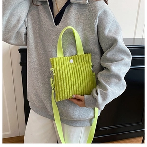 Detailed macro shot of neon yellow corduroy mini bag with textured vertical stripes and button