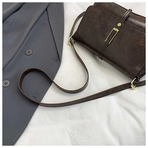 Detail of vintage dark brown leather crossbody bag with golden metal hardware and strap