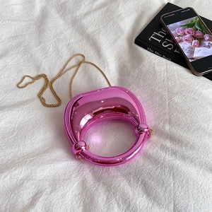 Chic pink metallic evening bag with circular handle and gold chain strap in a still life