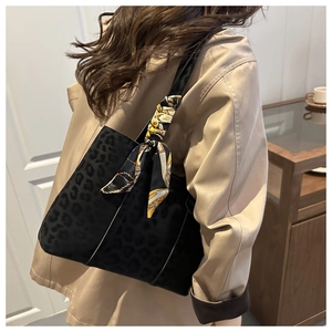 Détail d'un sac cabas léopard avec foulard en soie décoratif sur l'épaule du modèle