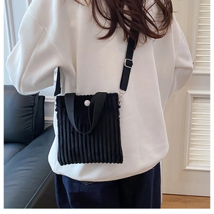 Close-up of black corduroy mini crossbody bag with white button and adjustable strap
