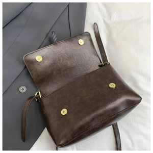 Detail of vintage brown tote bag with four brass magnetic buckles and oily leather texture