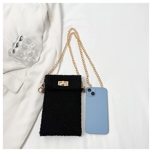 Detail of black plush mini crossbody bag with golden chain and twist lock on white surface