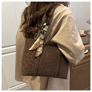 Vue détaillée du sac cabas en daim léopard avec foulard en soie sur un trench-coat beige