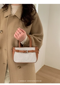 Détail du sac à main vintage en toile beige et cuir marron porté avec un manteau