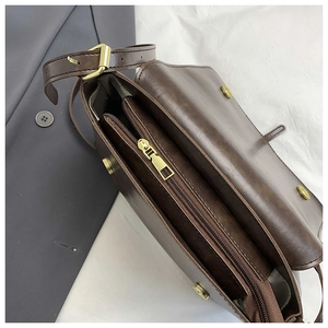 Macro shot showing double-compartment interior and gold magnetic clasp on brown leather bag