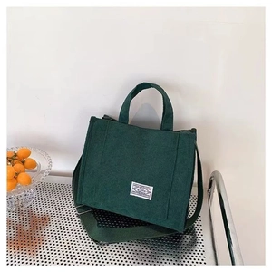 Deep green corduroy tote bag with adjustable strap and decorative label for casual use