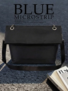 Close-up of minimalist black tote bag with large silver eyelets and wide woven strap