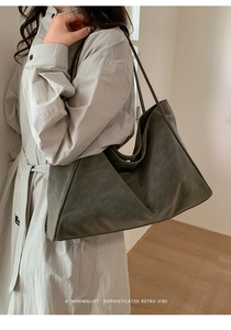 Dettaglio di una borsa tote retrò minimalista in pelle oliva scuro indossata