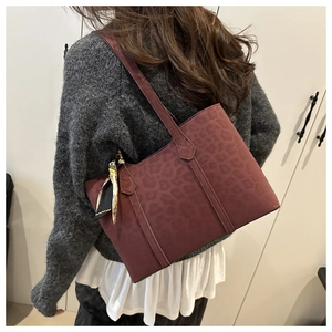 Detail of burgundy vintage tote bag with leopard print texture and silk scarf handle decor