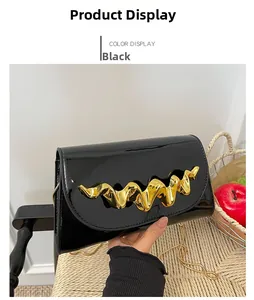 Detail einer glänzenden schwarzen Lackledertasche mit goldenem Wellen-Metallgriff-Dekor