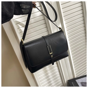 Close-up of black envelope tote bag with gold metal buckle and textured leather detail