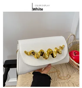 Detailansicht der weißen glänzenden Abendtasche mit goldener Metallverzierung und Kette