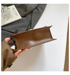 Detailed bottom view of a vintage dark brown leather crossbody bag with golden hardware