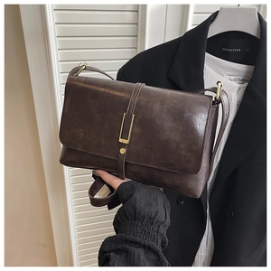 Detail of vintage brown faux leather shoulder bag with golden buckle and textured finish