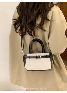Détail du sac à bandoulière en toile et cuir noir avec boucle de ceinture élégante