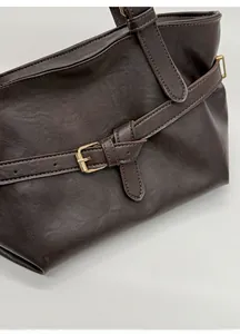 Dettaglio della texture in pelle marrone scuro con fibbia dorata e finiture