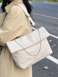 Detail of off-white padded tote bag featuring adjustable strap and silver chain accent