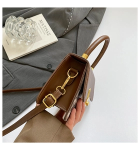 Detail view of the brown leather shoulder bag side accordion gussets and gold hardware