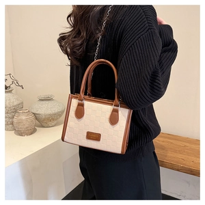 Detail of a retro tote bag with cream checkered texture, brown trim and chain strap