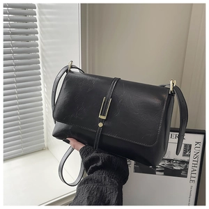 Close-up of black PU leather handbag with elegant gold metal buckle and flap cover