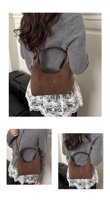 Detail view of brown suede underarm bag with smooth leather trim and adjustable strap