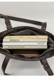 Interno capiente di una borsa tote in pelle marrone scuro con libri e portafoglio
