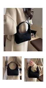 Detail view of black faux suede dumpling bag showing smooth texture and metal zipper