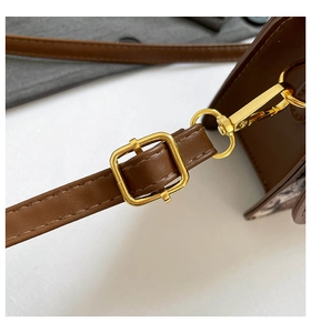 Detail of dark brown leather strap with gold metal buckle and stitching for crossbody bag