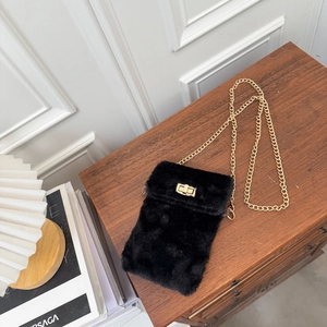 Plush black chain crossbody bag with gold turn-lock closure on vintage wooden surface