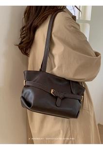 Dettaglio di una borsa a spalla retrò marrone scuro con fibbia dorata su una modella