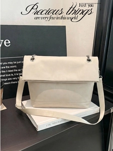 Detail of off-white minimalist tote bag with silver chain decoration and wide fabric strap