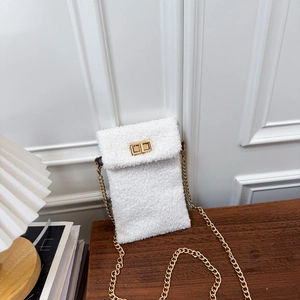 White faux fur small square crossbody bag with gold chain strap on a wooden table