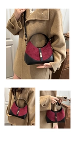 Close-up of burgundy suede handbag with black leather trim and gold metal buckle