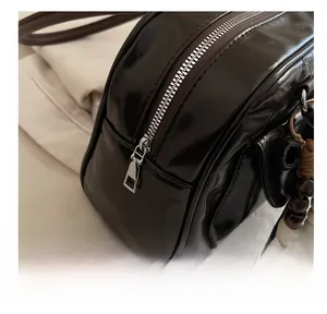 Detail of dark brown shiny bowling bag featuring a smooth silver zipper and wooden bead charm