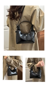 Black patent leather crescent bag detail with adjustable strap and glossy mirror finish