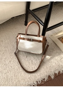 Detailaufnahme der Handtasche aus braunem Leder und Webstruktur mit Metallschließe