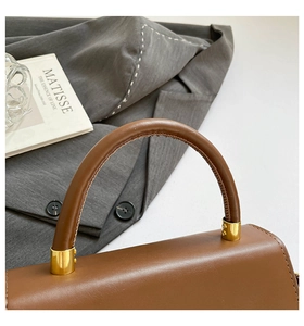 Detail shot of brown leather texture and gold hardware on a vintage crossbody bag