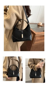Detailed view of the mixed-texture leather panel and gold metal buckle on a black handbag