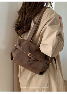 Dettaglio di una borsa a spalla vintage in pelle marrone con fibbia su una modella
