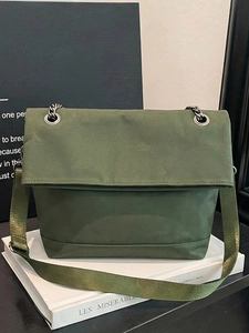 Detailed close-up of dark green canvas shoulder bag with silver chain and flap closure