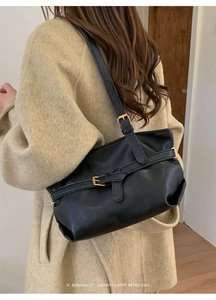 Close-up of black retro tote bag featuring golden buckle and textured leather finish