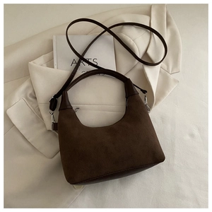 Macro detail of dark brown suede crescent bag with smooth leather strap and zipper closure
