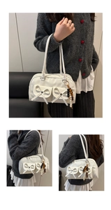 Detail of white Boston bag with bow pockets and multicolor wooden bead keychain