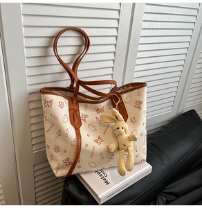 Minimalist beige tote bag with butterfly prints and rabbit plush charm on white books