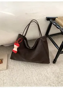Dettaglio borsa tote grande marrone scuro con ciondolo a mela rossa e chiusura