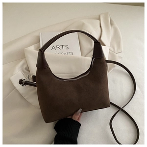 Detail of minimalist dark brown crescent bag with smooth matte suede texture and handle
