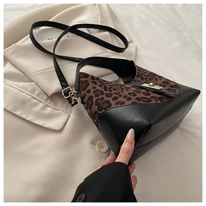 Détail du sac à bandoulière en daim léopard et cuir noir avec fermoir doré tournant